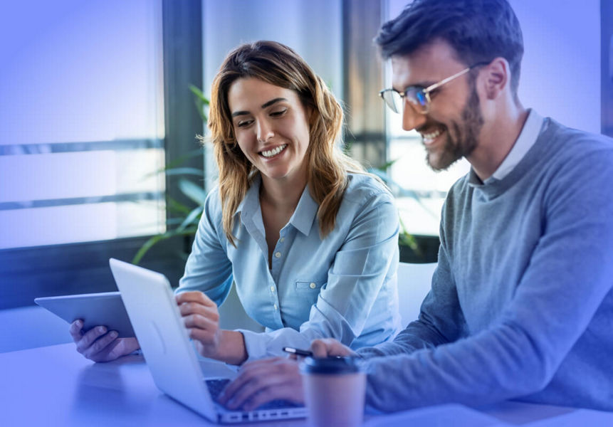 Two smiling professionals working on a laptop with a modernised application