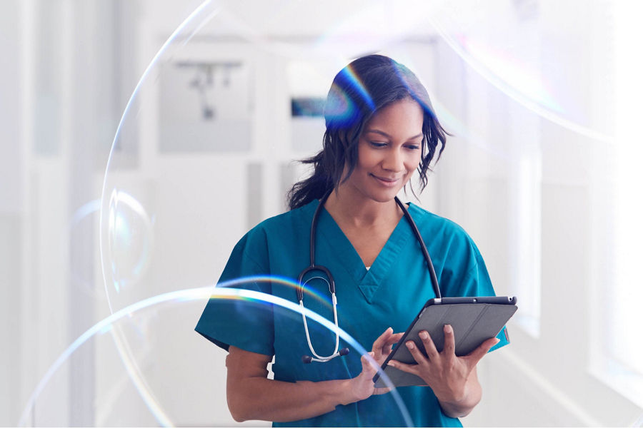 A woman wearing green scrubs looking at an electronic device.