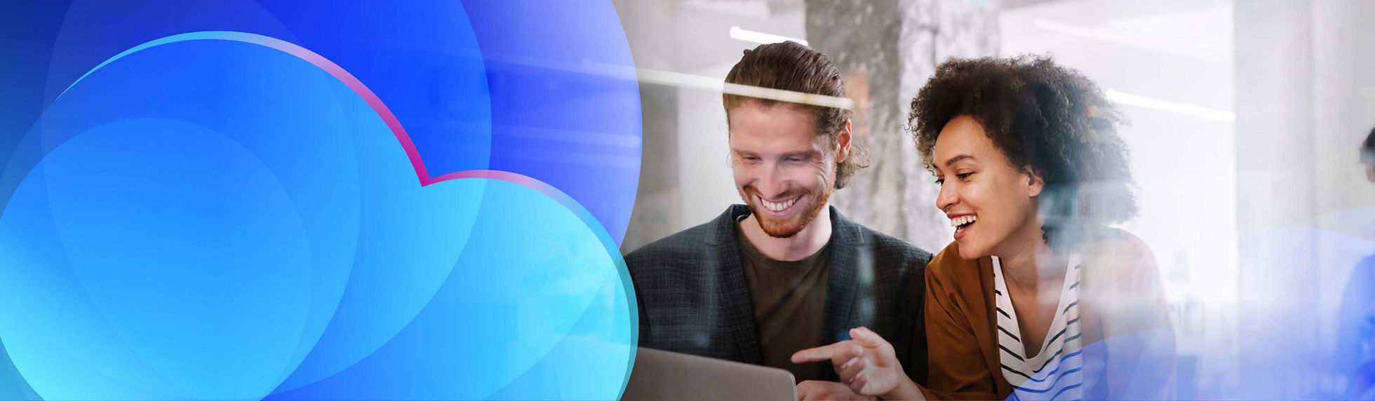 Two smiling cloud team members reviewing data on a laptop