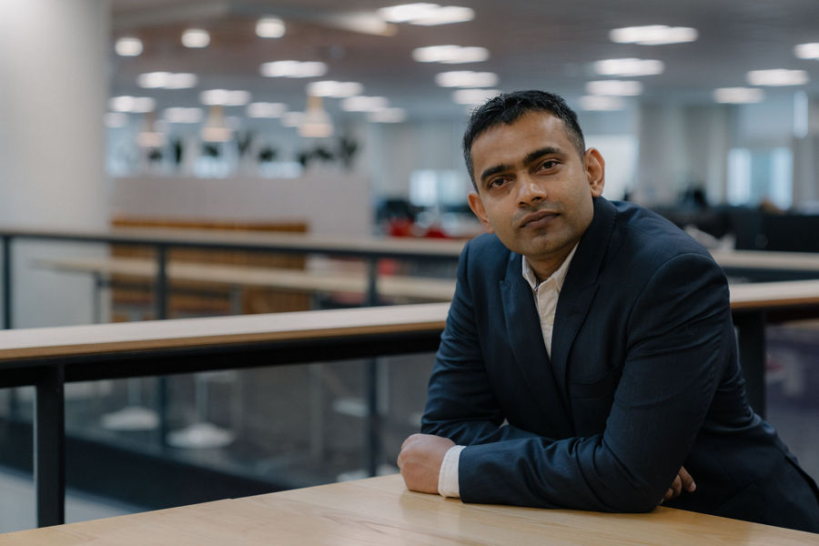 Anish leaning on table wearing a suit