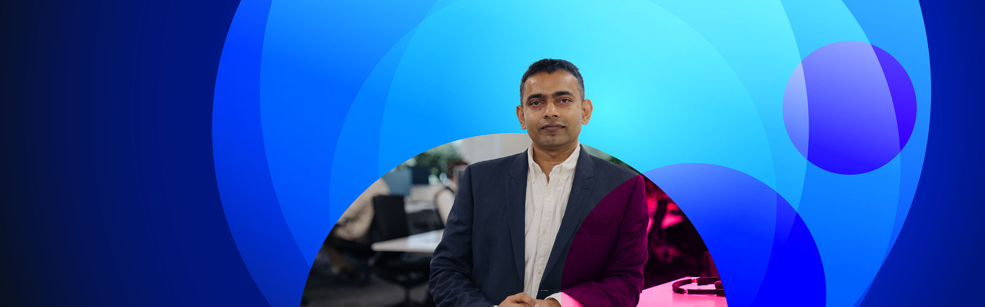 Anish Sharma mid distance profile shot with office background cropped for Datacom Discover banner with colourful lens inspired blue background design and transparent pink circles overlaid