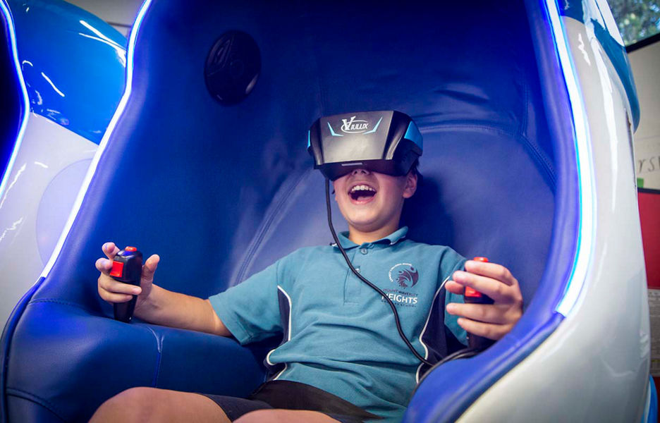 Smiling young student sitting in a VR booth wearing a VR headset