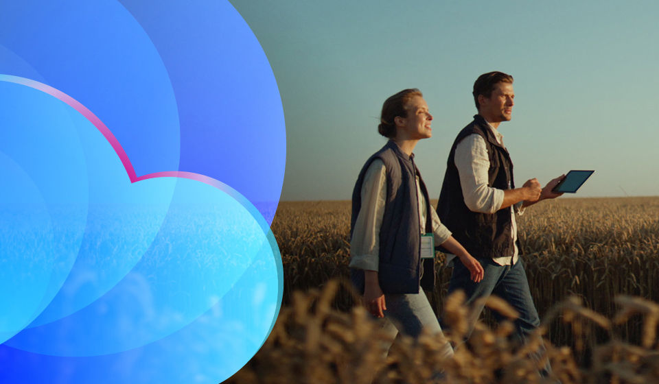A man and woman holding a tablet walking in a field