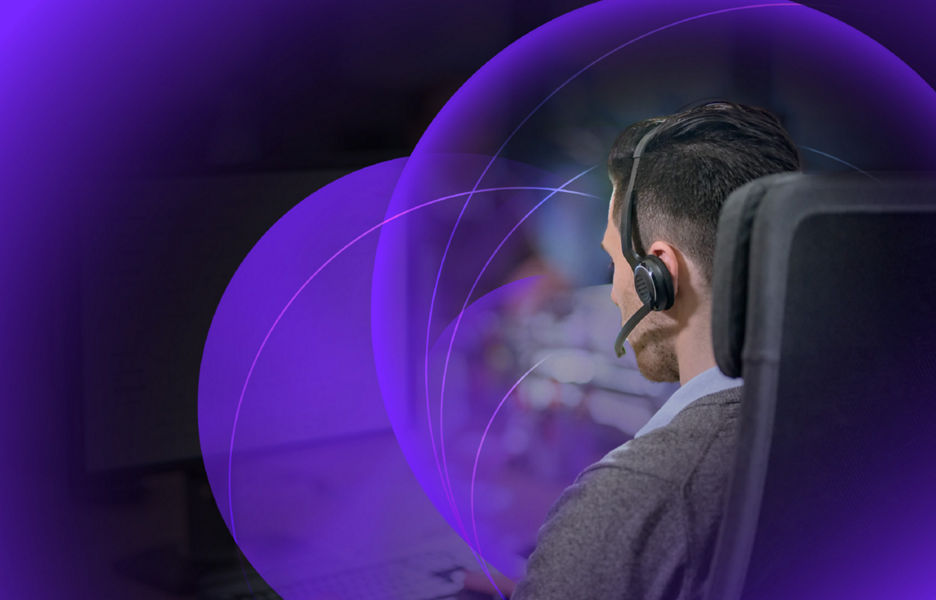 Man sitting at desk working on computer with a headset on