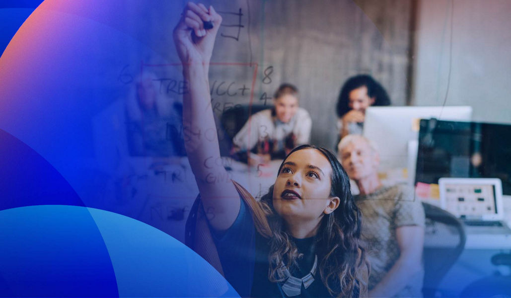 A CX strategist writing a customer experience strategy on a glass wall with team members in the background.
