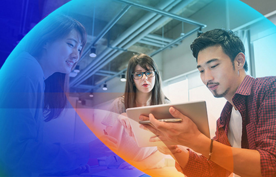 Three people having a conversation in an office space while look and pointing at an iPad