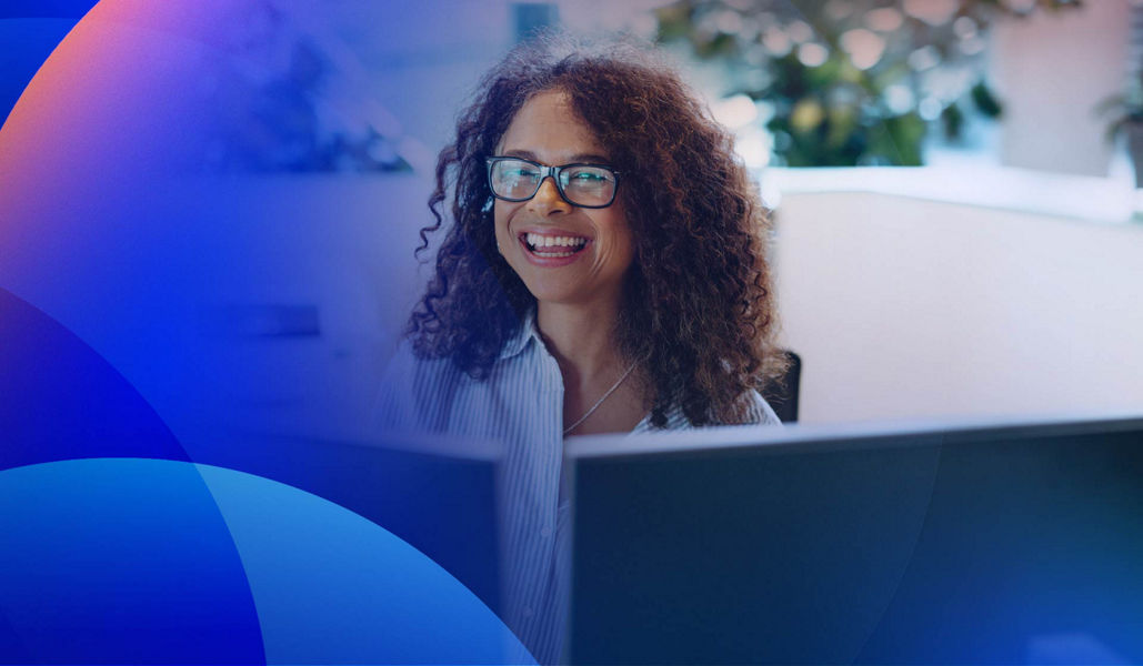 A smiling women working in front of multiple screens in a government office.