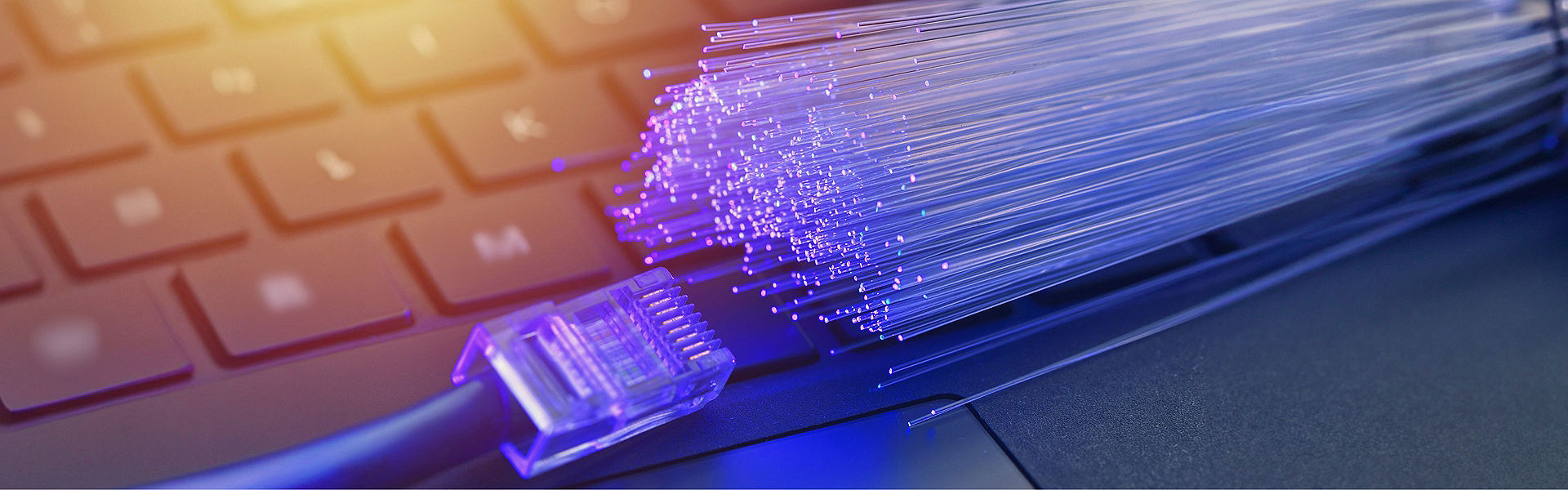 Broadband fibres and cable laying on a keyboard with blue and golden light