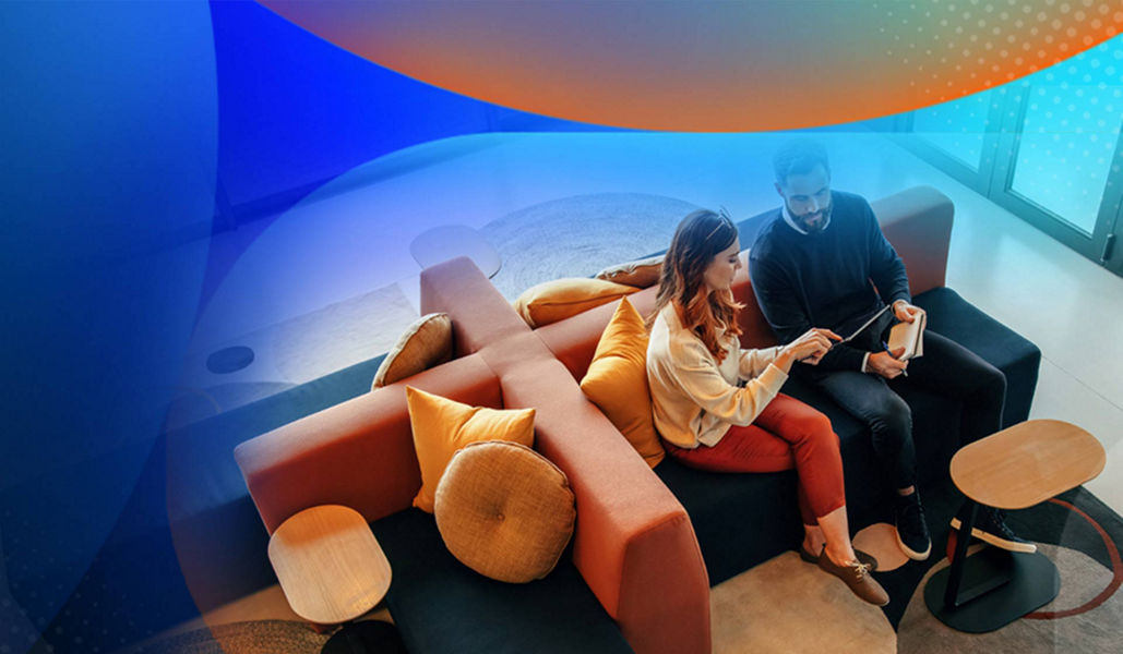 Two people sitting on a couch in a corporate setting with windows behind them with an orange and blue lens overlay