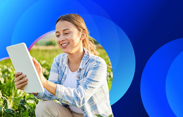Woman sitting in a farm field looking at tablet