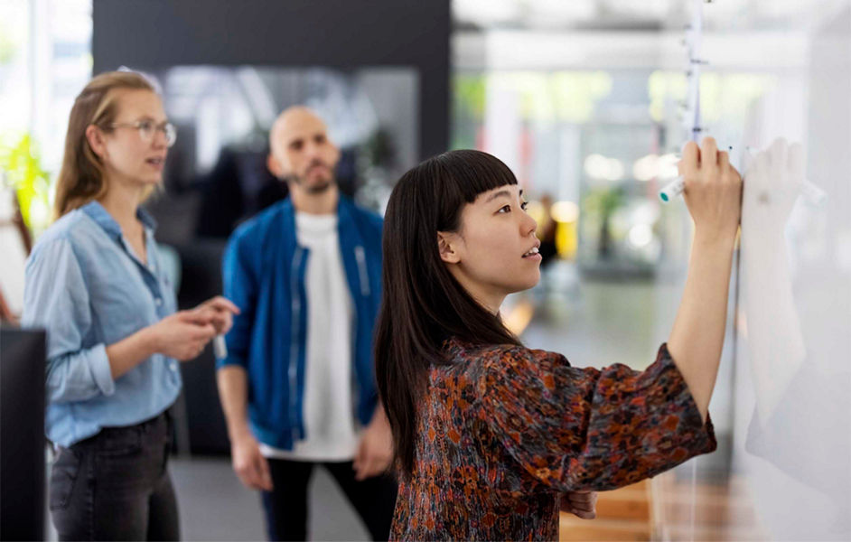 A group of people running a workshop with a woman writing on a whiteboard