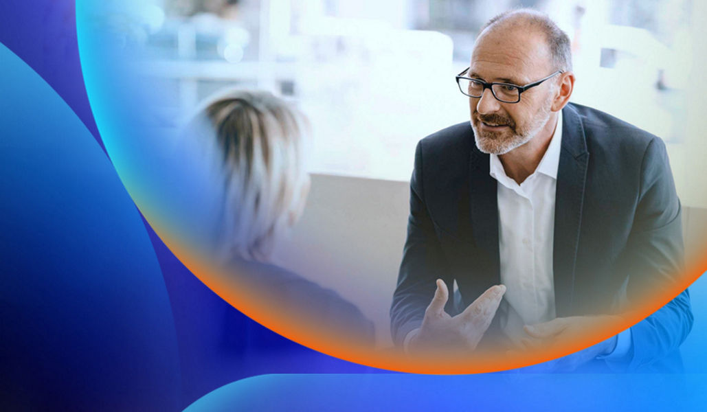 Man in a corporate office with window behind him talking to a woman who is making hand gestures with an orange and blue lens overlay