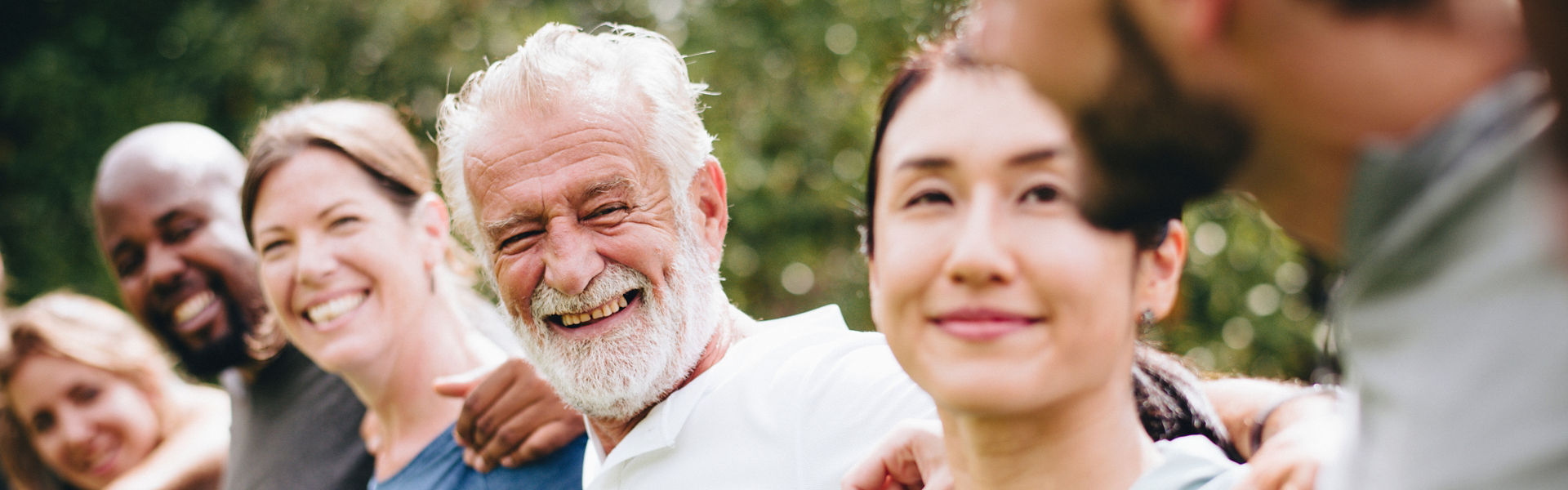 Community of diverse people spending time together outdoors, arms around each other