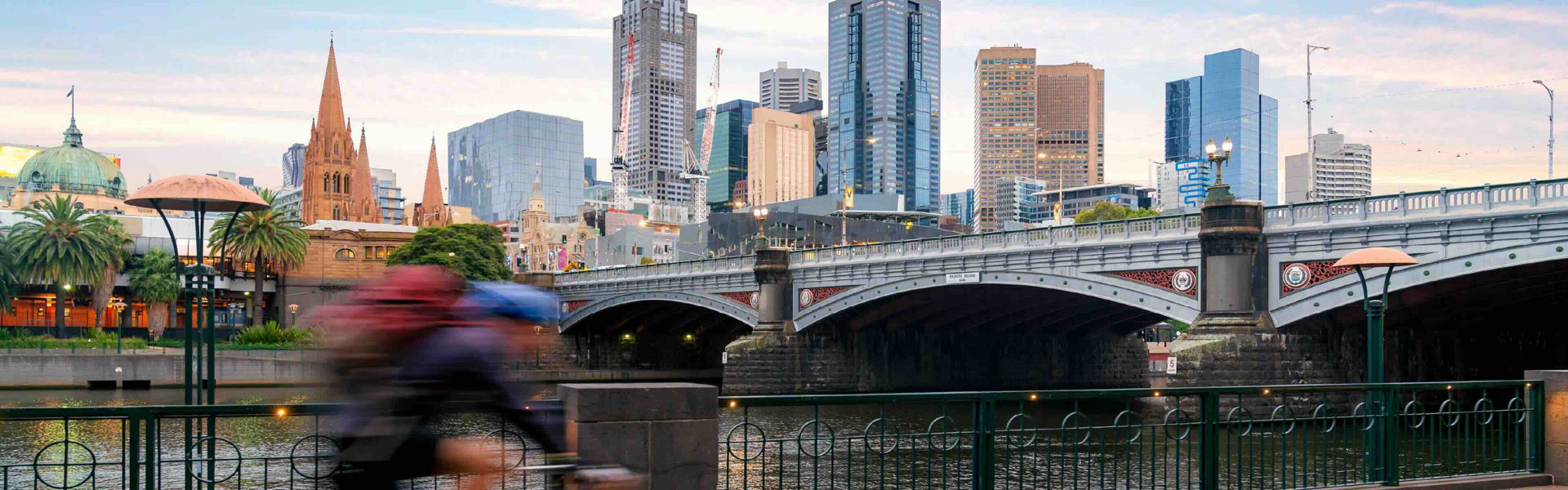 Australian people cycling for exercise near Yarra River with view of the Melbourne City Financial District with skyscrapers in morning at Melbourne, Victoria, Australia