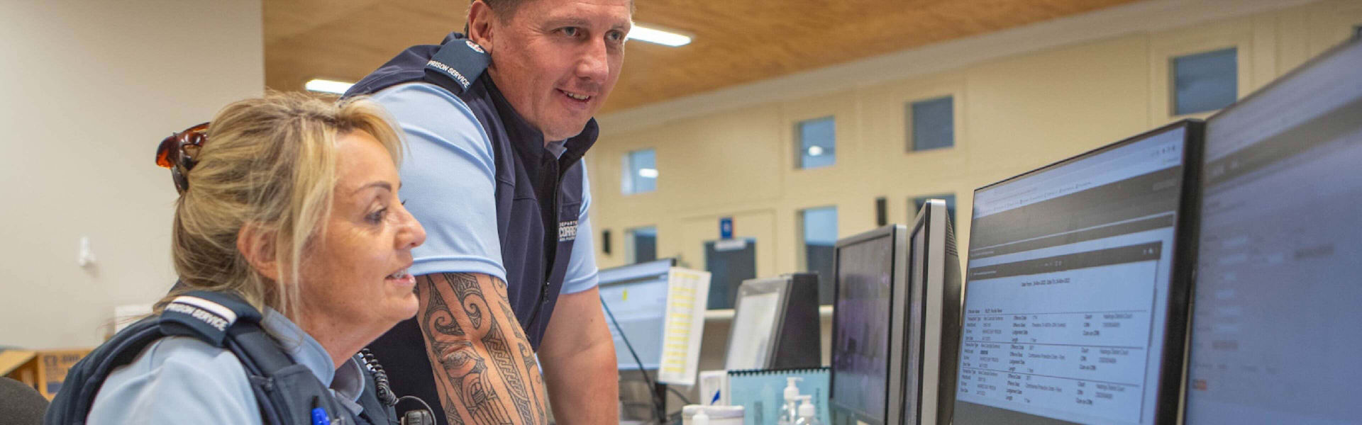 Two Department of Corrections employees looking at information collaboratively on a desktop.
