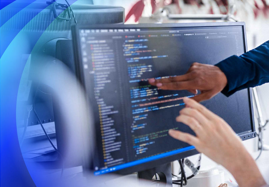 A woman and reviewing code on a computer monitor