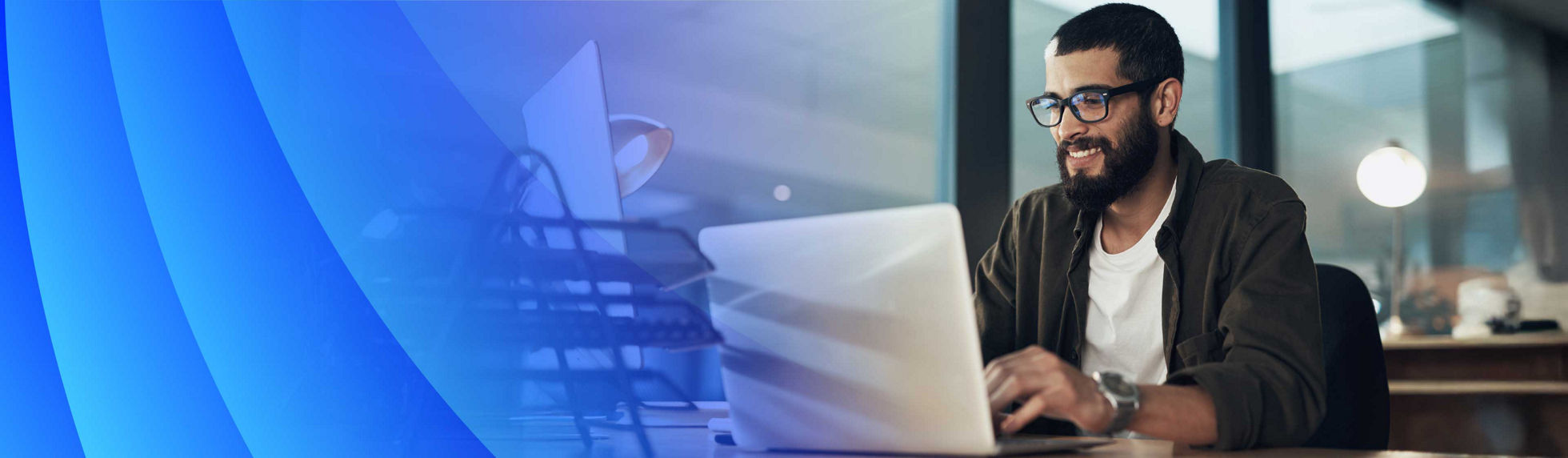 Man in an office smiling while on laptop