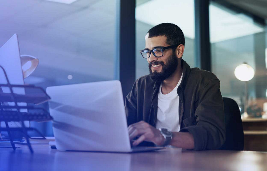 Man in an office smiling while on laptop