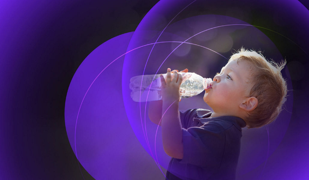 A young boy drinking a bottle of water outside