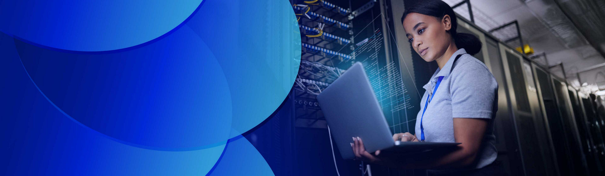 A woman standing, working on laptop screen in a data centre