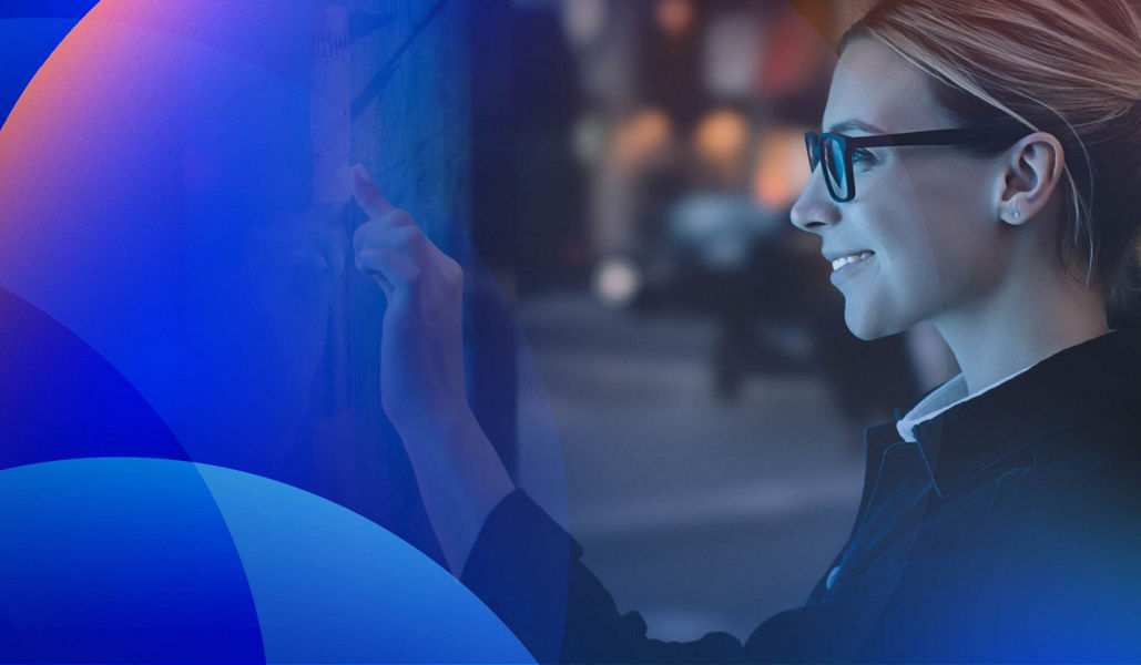 A smiling young woman interacting with a large public digital sign