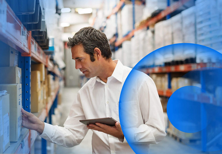A man in a warehouse taking stock of boxes on a tablet