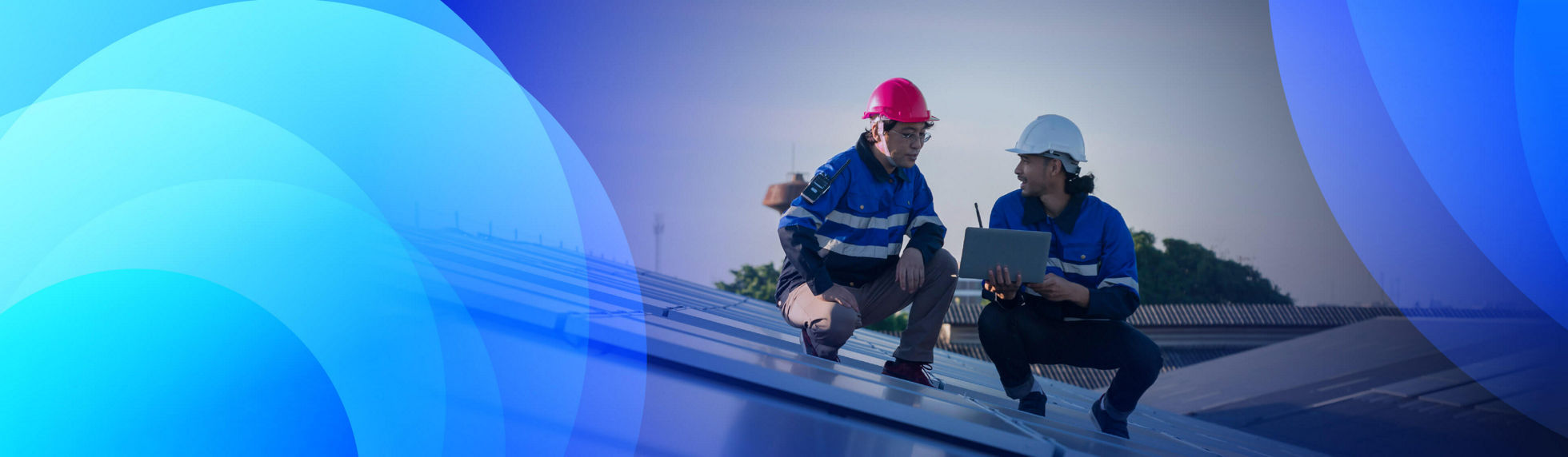 Two energy specialists on a roof running tests on a laptop