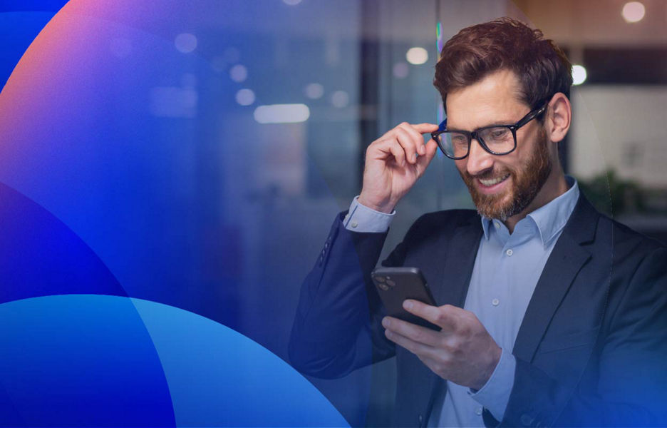 Professional smiling while looking at a smartphone and adjusting their glasses in an office.