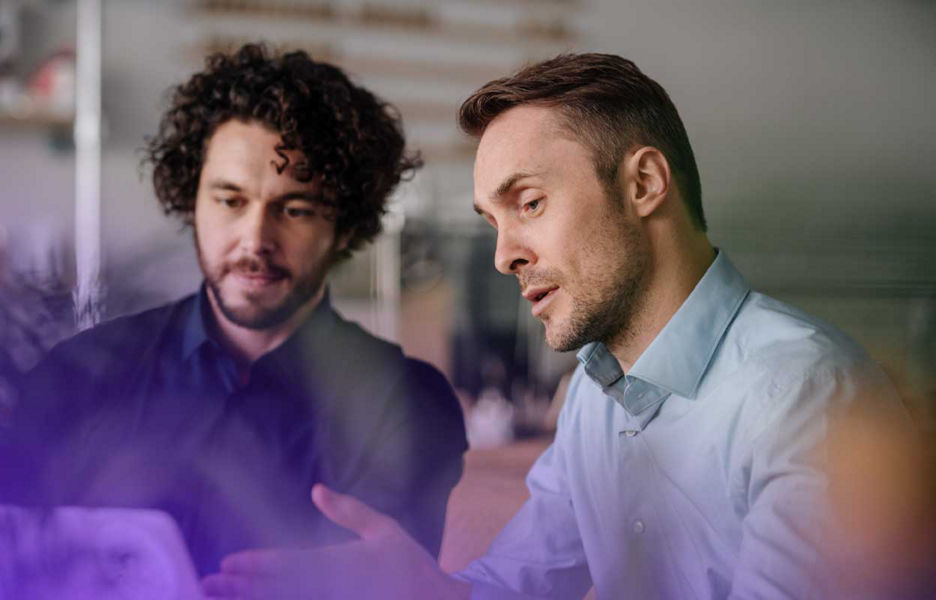 Two men looking at laptop screen together and talking