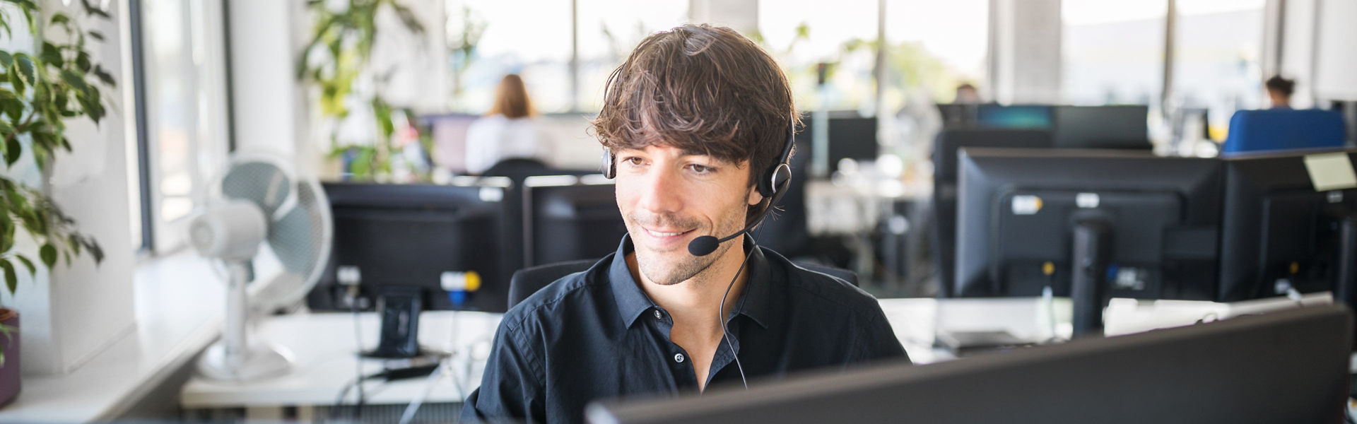 A woman with a headset working on a computer in a call centre