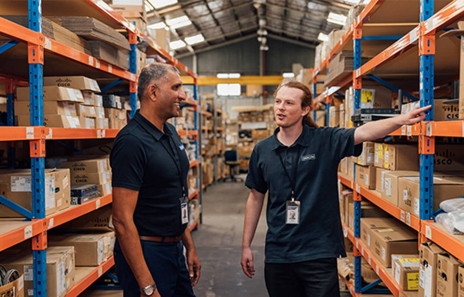 Two warehouse workers standing in a stock aisle