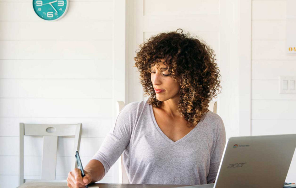Woman taking notes while using a chromebook