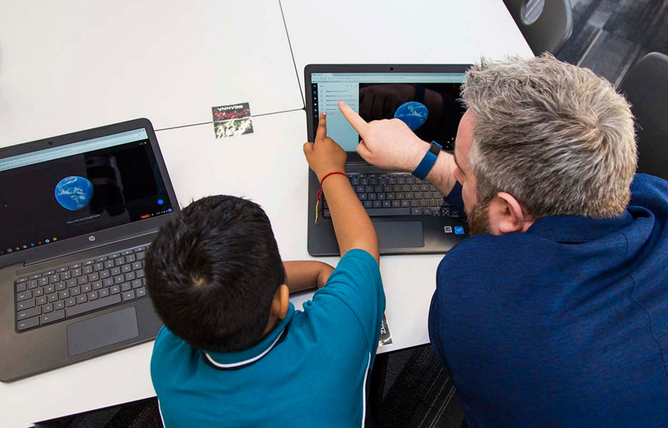 A child and an adult using a touchscreen laptop for learning