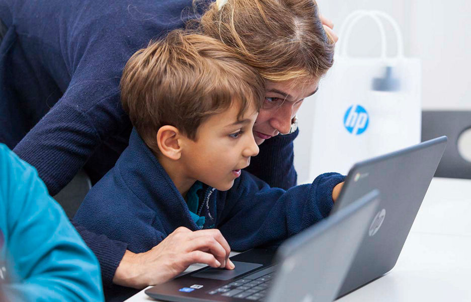 A child and an adult using a laptop for learning