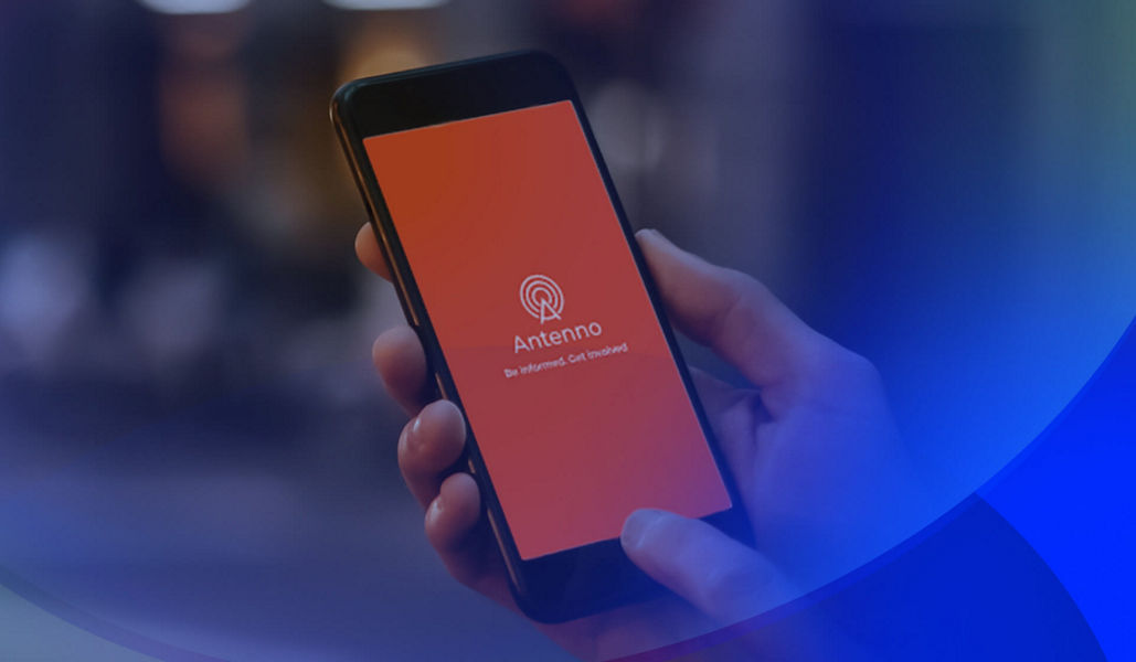 A hand holding a smartphone displaying the Antenno app on the screen.