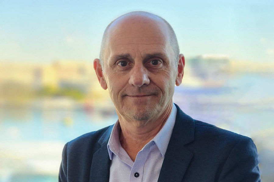 A portrait of Greg Furlong in front of a harbour