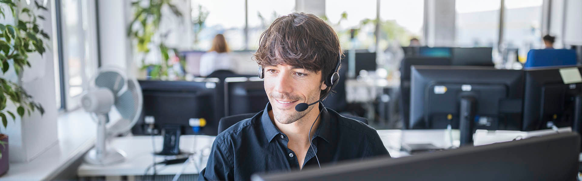 A young customer service representative taking a call in an office