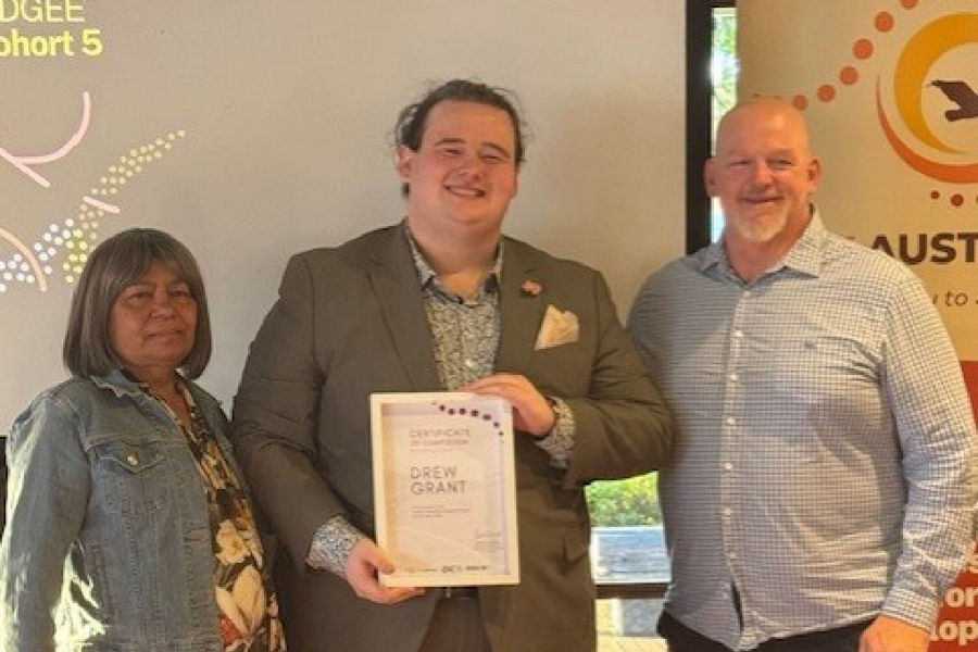 Drew Grant smiling with certificate at IDEP graduation