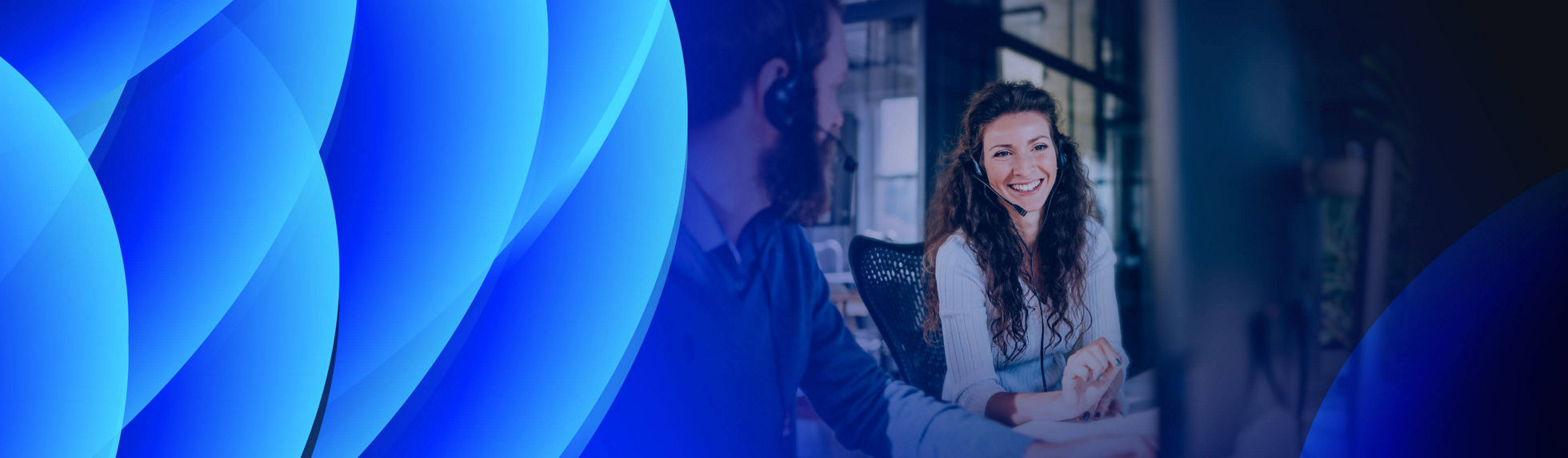 Smiling young woman with a headset working with a male colleague.