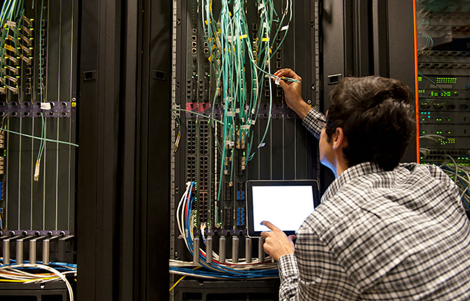 A man holding a device inside a server room