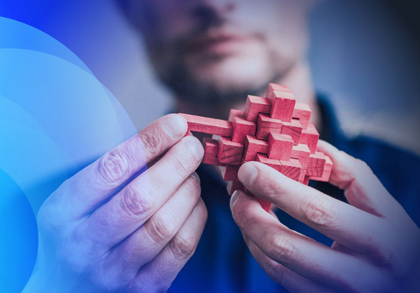A man holding a pink wooden puzzle and sliding a block into place