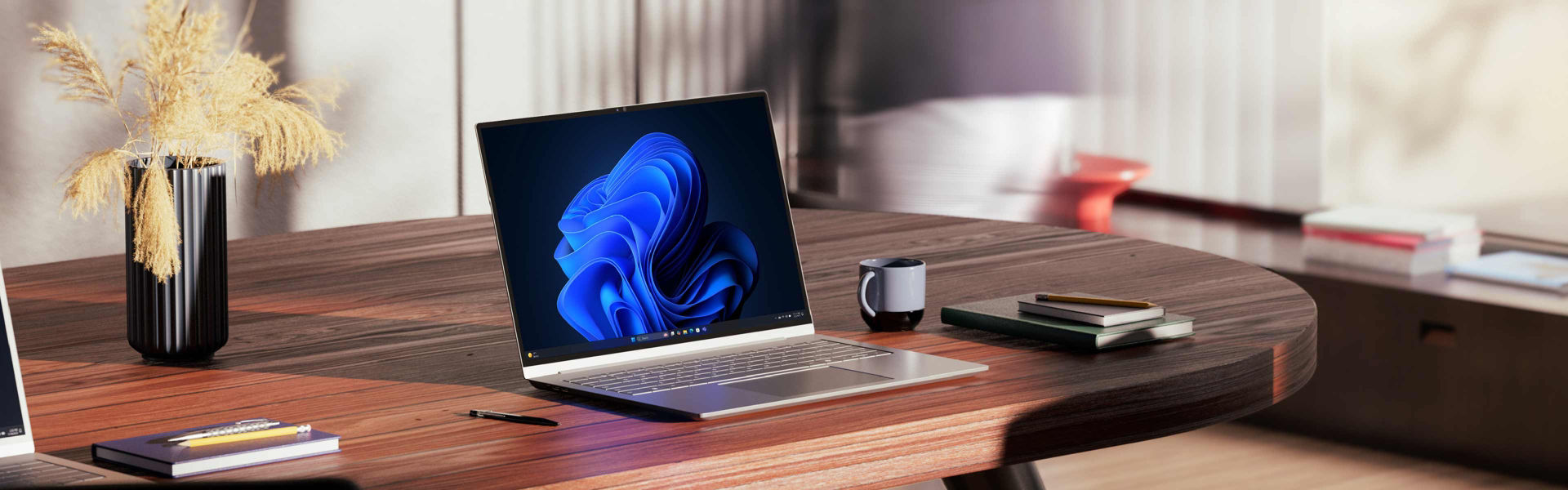 HP laptop open on a desk in a home office with a blurred person walking in the background