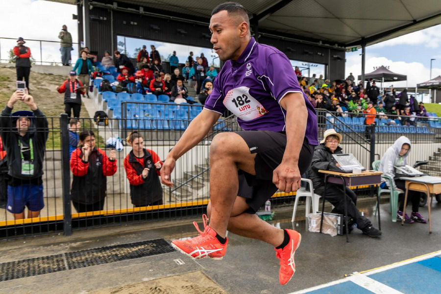 A photo of Lutu airborne in action as he competes in the long jump