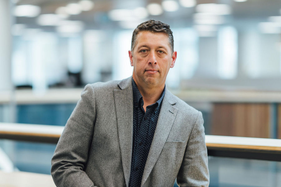 Portrait of Justin Gray in office with blurred background, blue tones and soft lights
