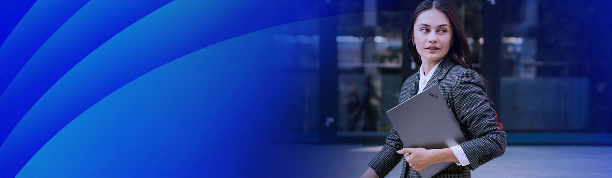 Woman walking and looking to the side with a laptop under her arm