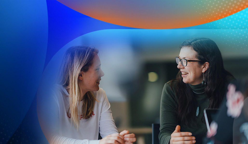 Two woman having a conversation at their desks in an office with an orange and blue lens overlay