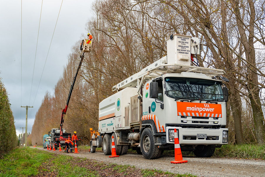 A mainpower truck on a road next to trees