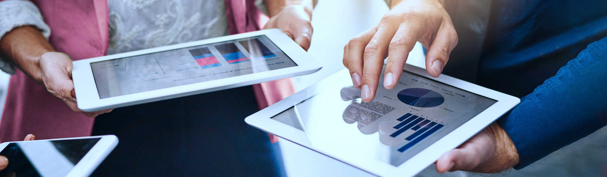 hand tapping on a tablet with graphs on the screen