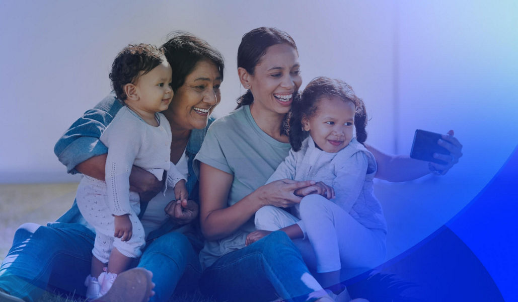 A mother taking a selfie with her two children and her own mother, all smiling together.