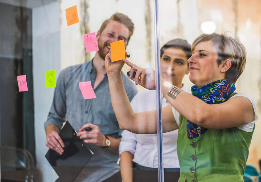 Three colleagues using sticky notes on a whiteboard